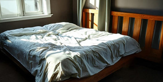 Latex mattress sag creates visible dips and uneven sleeping surface on an unmade bed near a sunlit window.