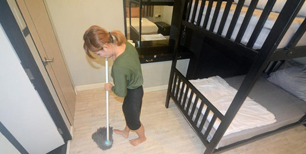 Student tidying a dorm room with a bunk bed
