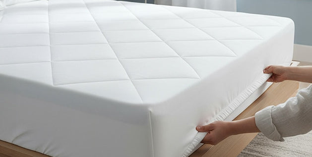 Quilted mattress protector fitted snugly on a bed, illustrating how to wash a mattress protector without damage.