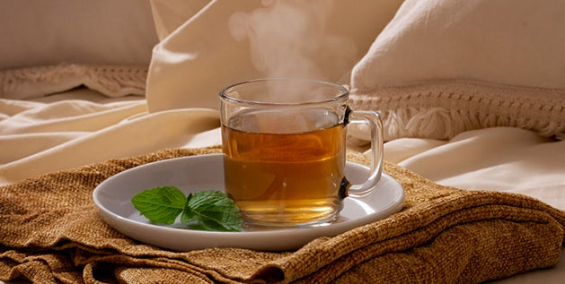 A steaming cup of herbal tea on a nightstand - Best sleep hacks for a good night's rest