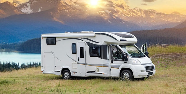 Class C motorhome parked in a mountain meadow at sunset, capturing the freedom of full-time RV living.