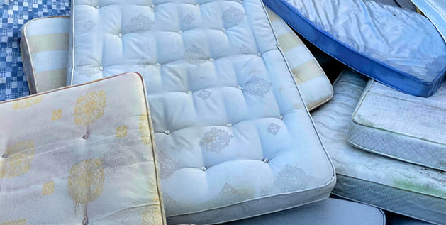Pile of discarded mattresses stacked outdoors, ready for mattress recycling and material separation.
