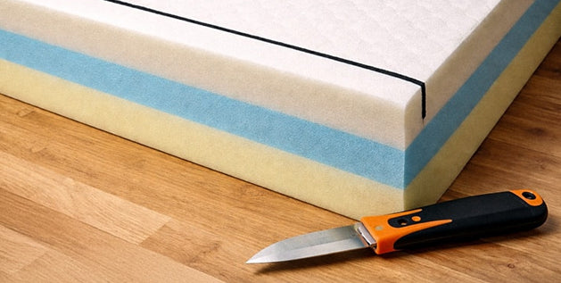 Cross-section of a foam mattress ready to be cut with a sharp utility knife along a marked line.