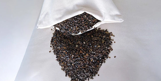 Buckwheat hull filling used inside pillows, shown in loose form on a white surface.