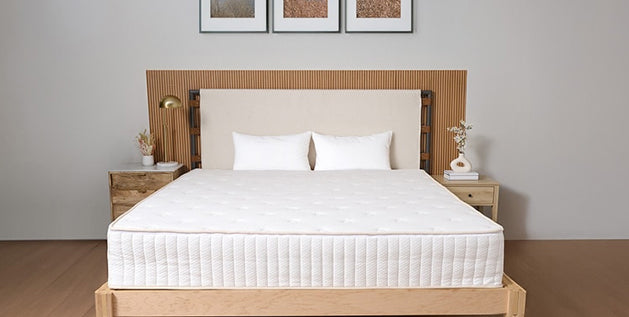 Bedroom featuring a natural mattress on a wooden platform bed with cream headboard and framed nature photos above.