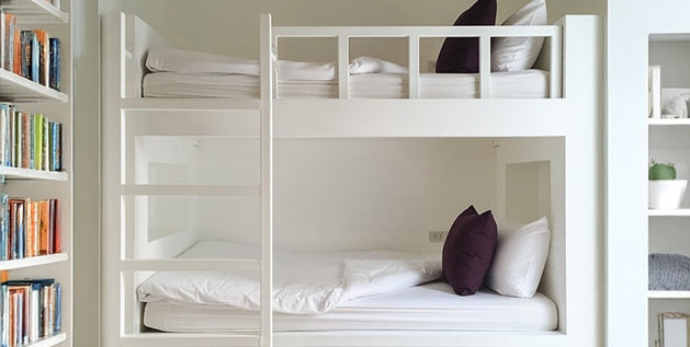 White bunk beds show typical dorm bed size and layout in a small shared room.