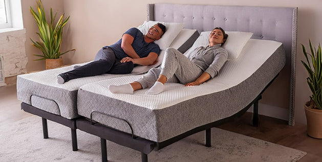 Couple relaxing on a split adjustable bed with raised head sections, the woman's knees slightly lifted, in a bedroom.